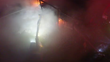 excavator breaking wall during rescue operation to control fire and smoke at night in farnham, québec, canada.