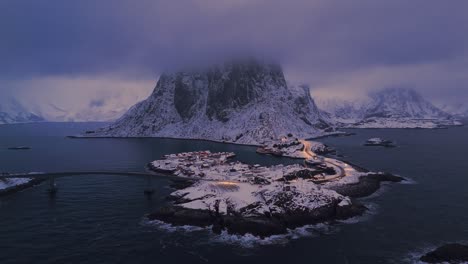 hamnøy lofoten in the foggy evening light with snow-covered houses and a sky overcast with dark clouds and fixed camera