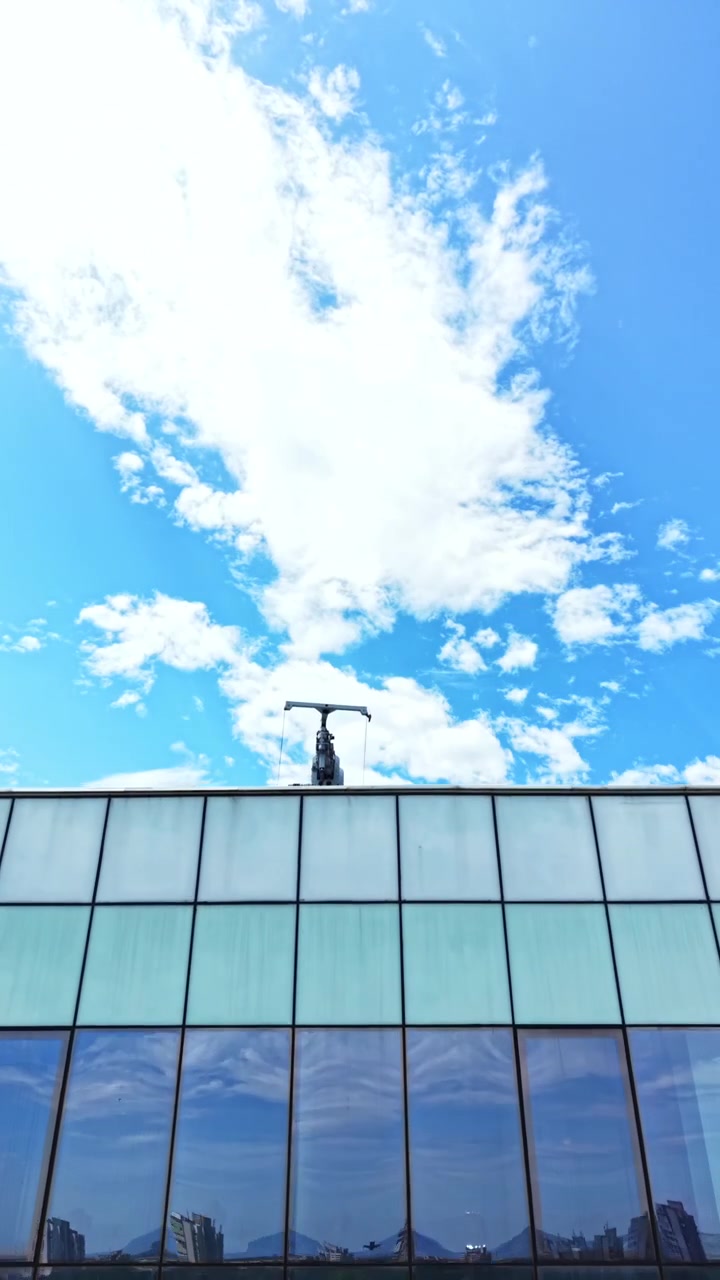 Reflejo del cielo y las nubes en un edificio de cristal en una zona urbana durante el día.