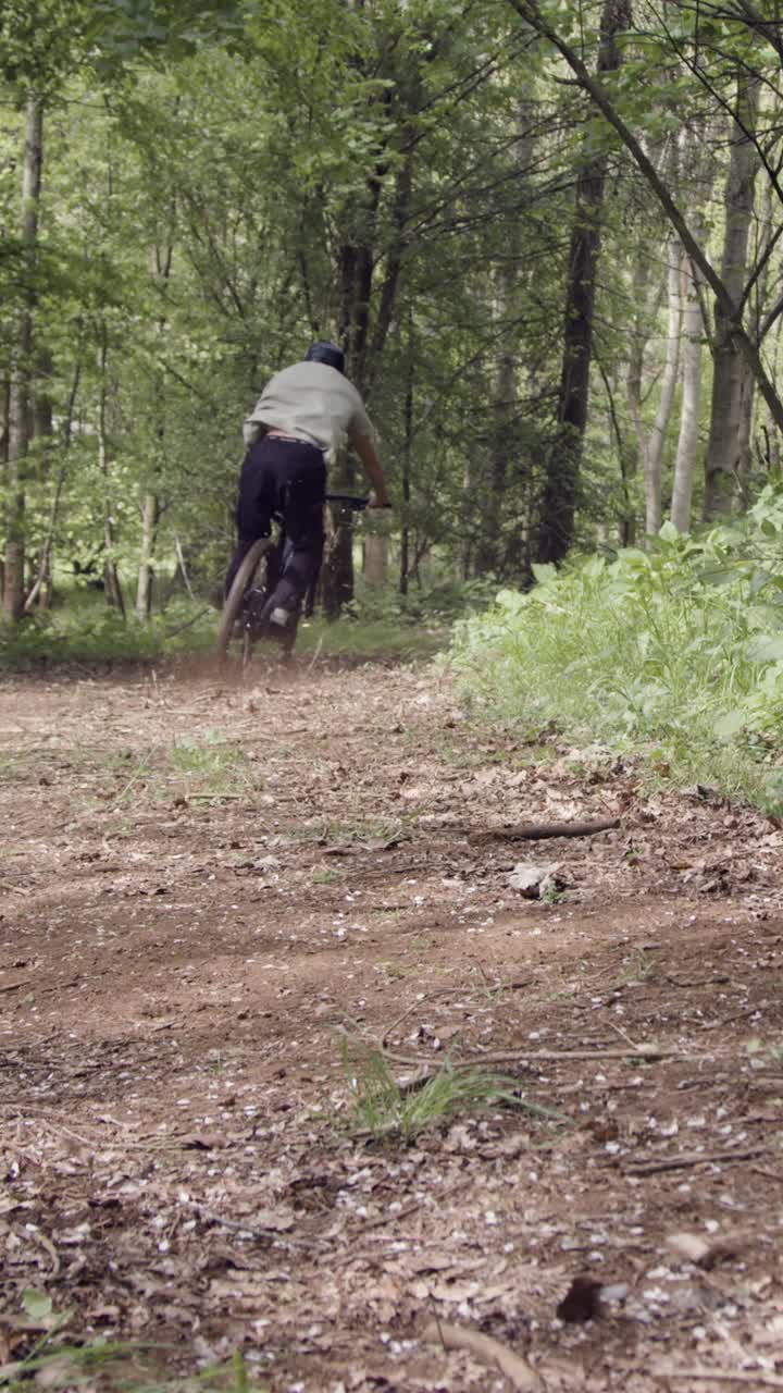 video vertical cercano de un hombre en bicicleta de montaña ciclando a lo largo de un sendero de tierra a través del bosque 2