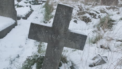 in loving memory crucifix cross headstone in snow covered graveyard