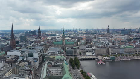 Fly-above-Binnenalster-lake.-Aerial-view-of-city-centre-with-old-city-hall-building-and-churches.-Harbour-cranes-in-background.-Free-and-Hanseatic-City-of-Hamburg,-Germany