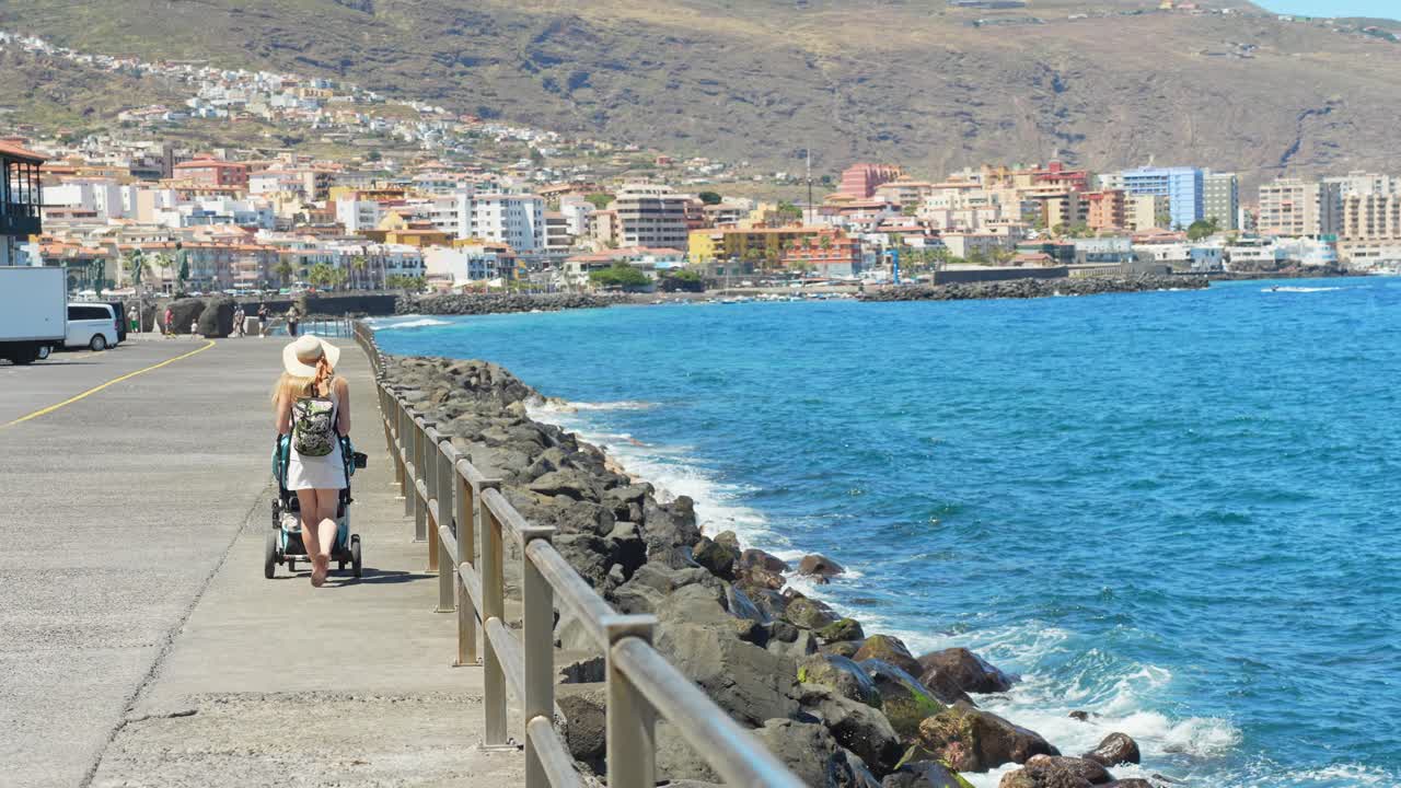 Mother with a stroller walking on a pier on vacation in Tenerife, Spain