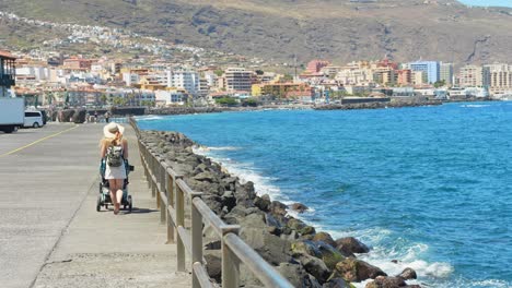 mother with a stroller walking on a pier on vacation in tenerife, spain