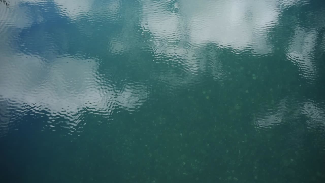 Beautiful turquoise water surface reflecting a pretty sky in soft ripples