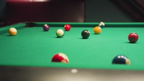 billiard balls scattered across green pool table after break shot, captured in motion. vibrant colors and dynamic positioning create sense of action in pool hall, highlighting competition, precision