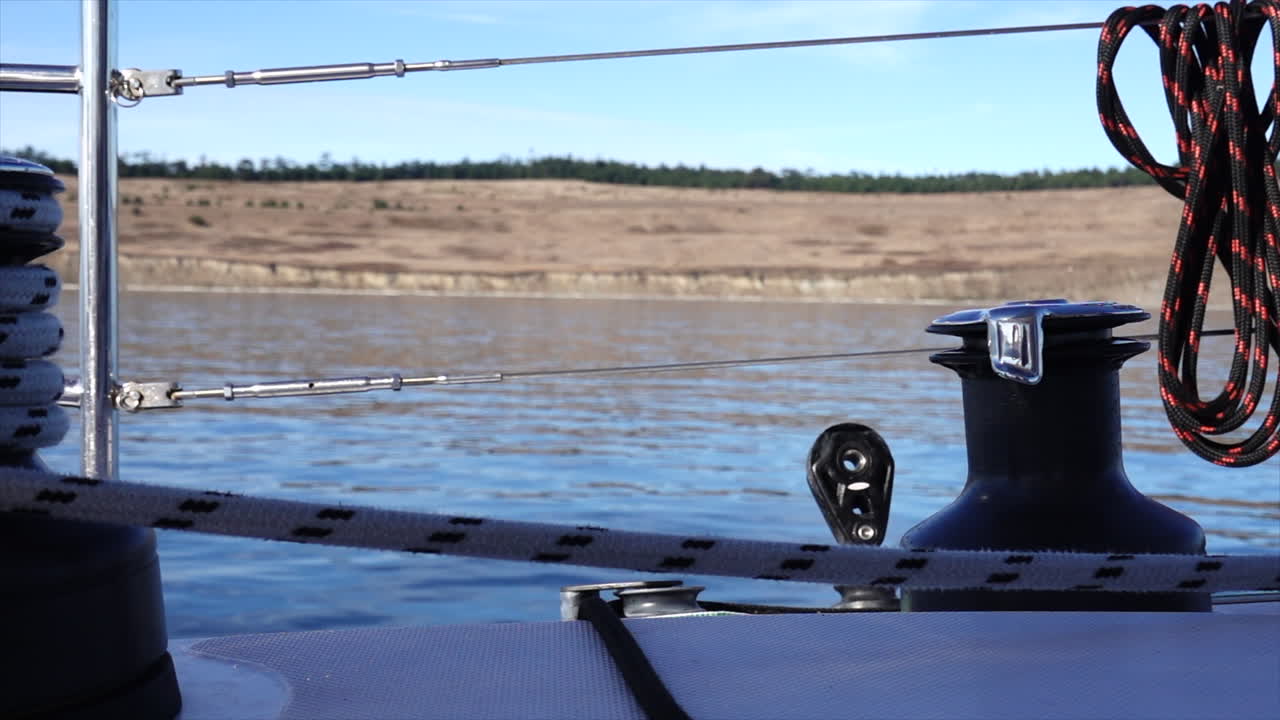 Camera looking starboard off a sail boat at the shores of the San Juan Islands
