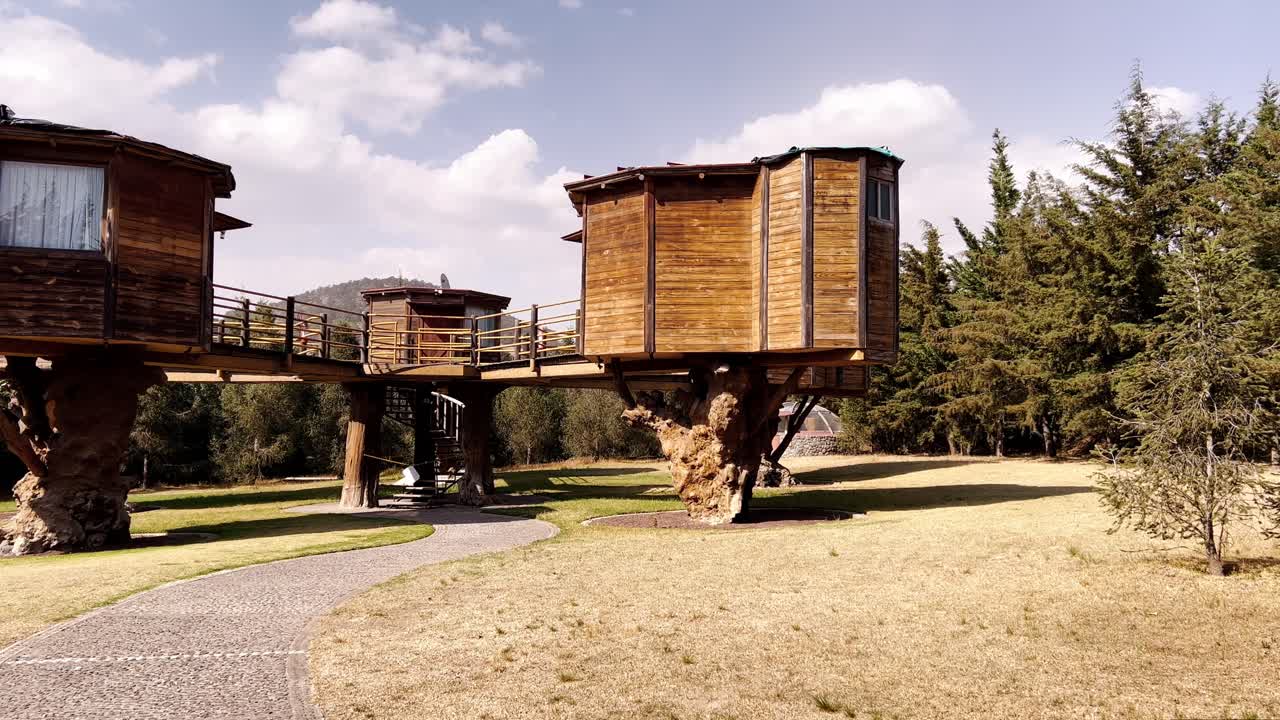Pan shot of house on stilts during the day with cloudy sky and sun, outdoor