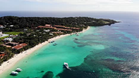 Drone-Volador-En-La-Playa-De-Roatán-Con-Agua-Azul-Cristalina-Y-Barcos-En-4k