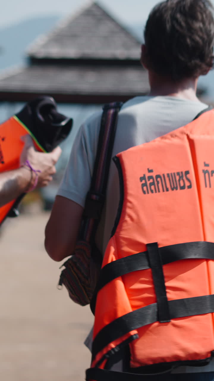 Uomini che camminano sul molo con i giubbotti di salvataggio