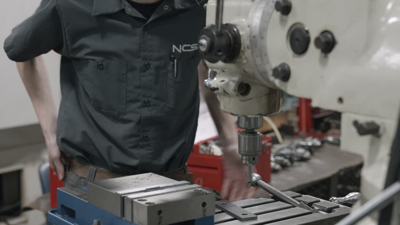 Machining apprentice trade school student changes a drill bit on a milling machine
