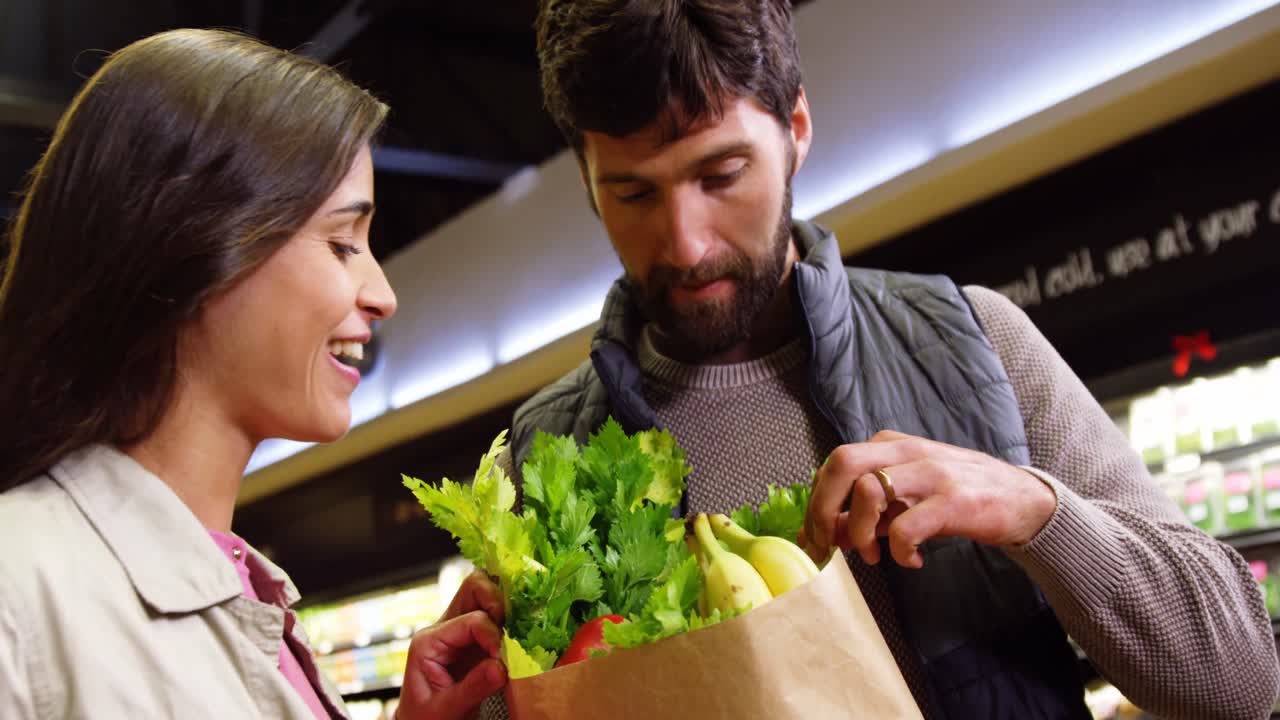 pareja sonriente comprando verduras en la sección orgánica