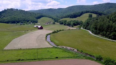 AERIAL-HIGH-PULLOUT-OF-HAY-FIELD-AT-HARVEST-TIME-IN-SUGAR-GROVE-NC-NEAR-BOONE-AND-BLOWING-ROCK-NC,-NORTH-CAROLINA