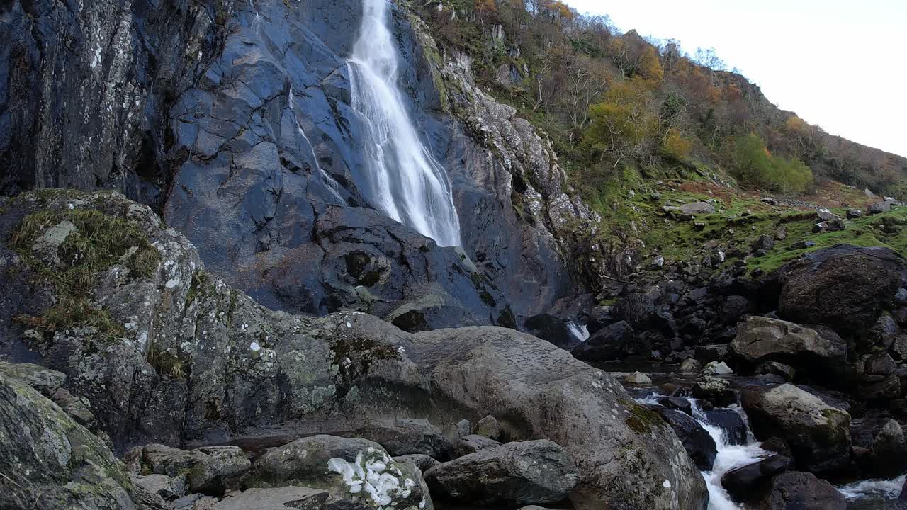 Cascata rocciosa che scorre su rocce fluviali frastagliate e massi, timelapse