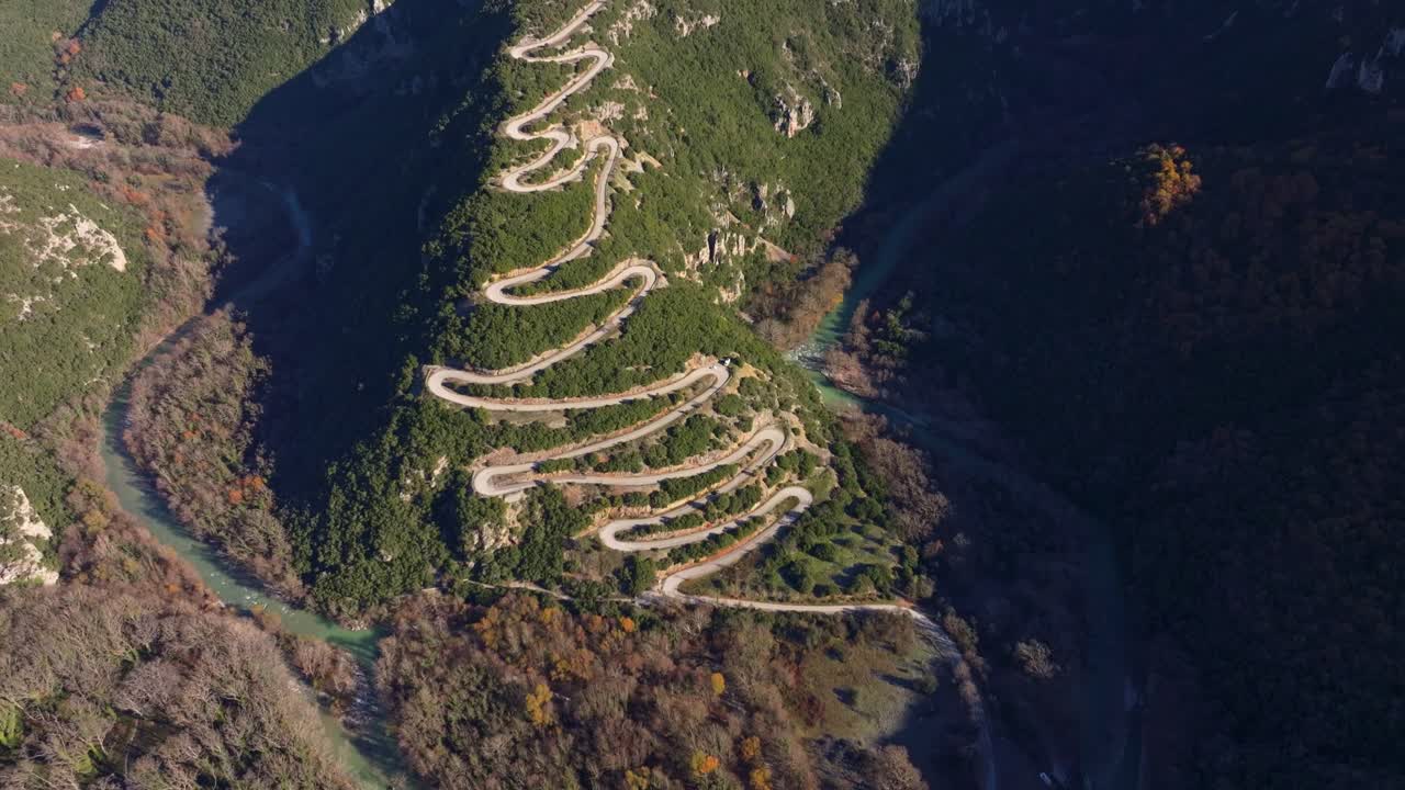 Drone scene of mountain road winding beneath forest canopy