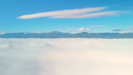 carpet of clouds, thick cloud layer with mountain background, white sea of mist with clear blue sky, cloud covered mountain valley with mountain range