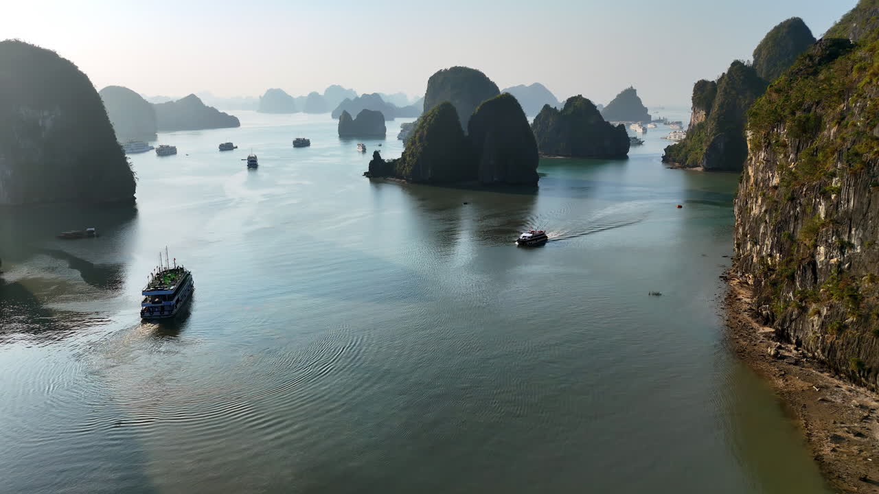 Luchtopname met drone van boten die varen tussen kalkstenen karst eilanden in Ha Long Bay, Vietnam, een UNESCO Werelderfgoedlocatie bekend om zijn spectaculaire zeegezicht.