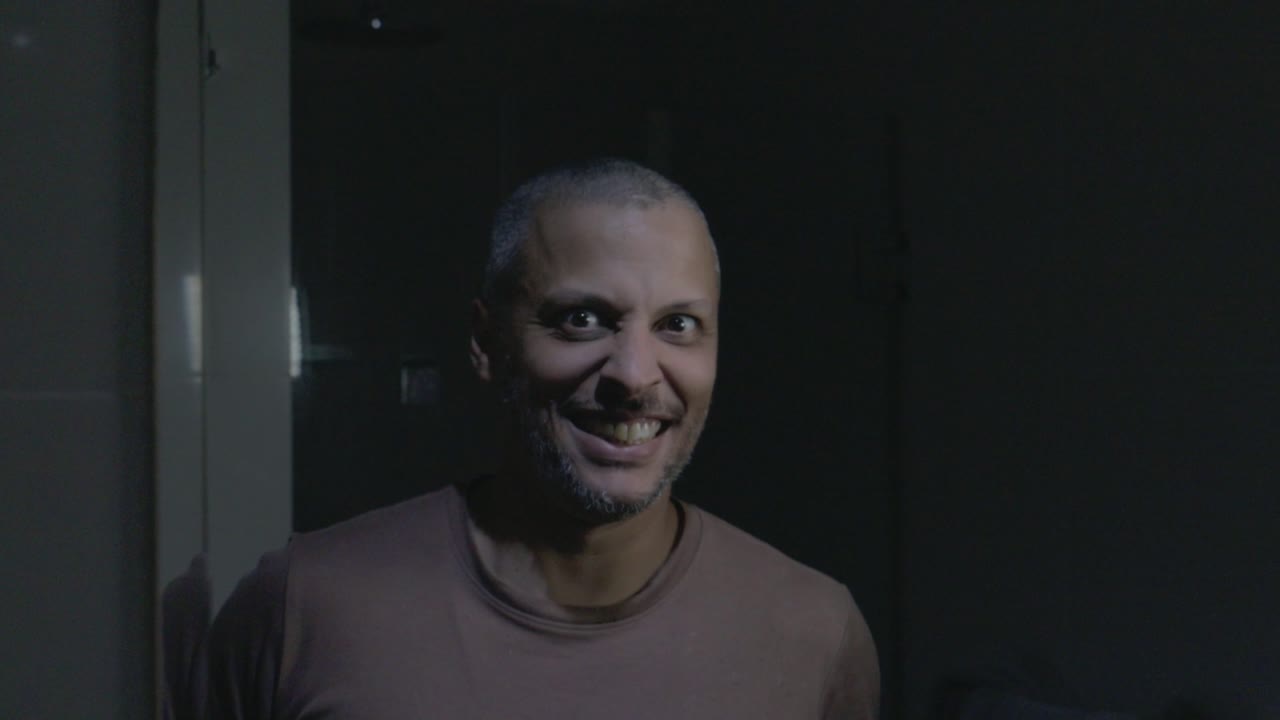 Uomo che si rade la barba con un regolabarba elettrico e fa espressioni facciali