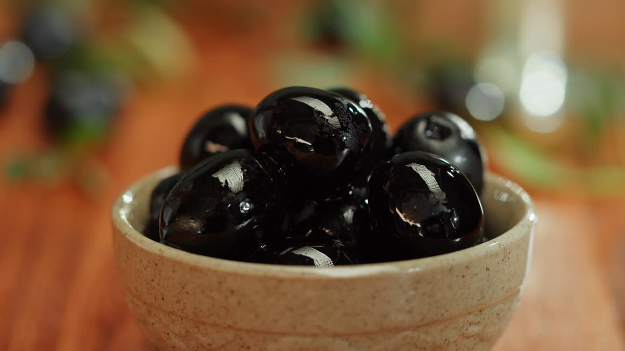 Hand Picking Black Olives from a Bowl