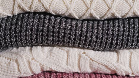 warm knitted clothes, lying neatly stacked on the shelf. tilt shot