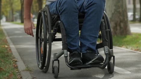 hombre con discapacidad en silla de ruedas camina por el callejón del parque