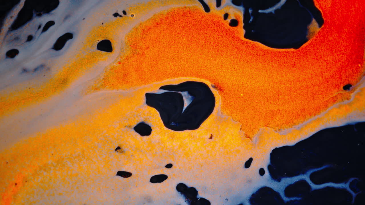 Abstract close-up of ink mixing, swirling with vivid orange and black hues