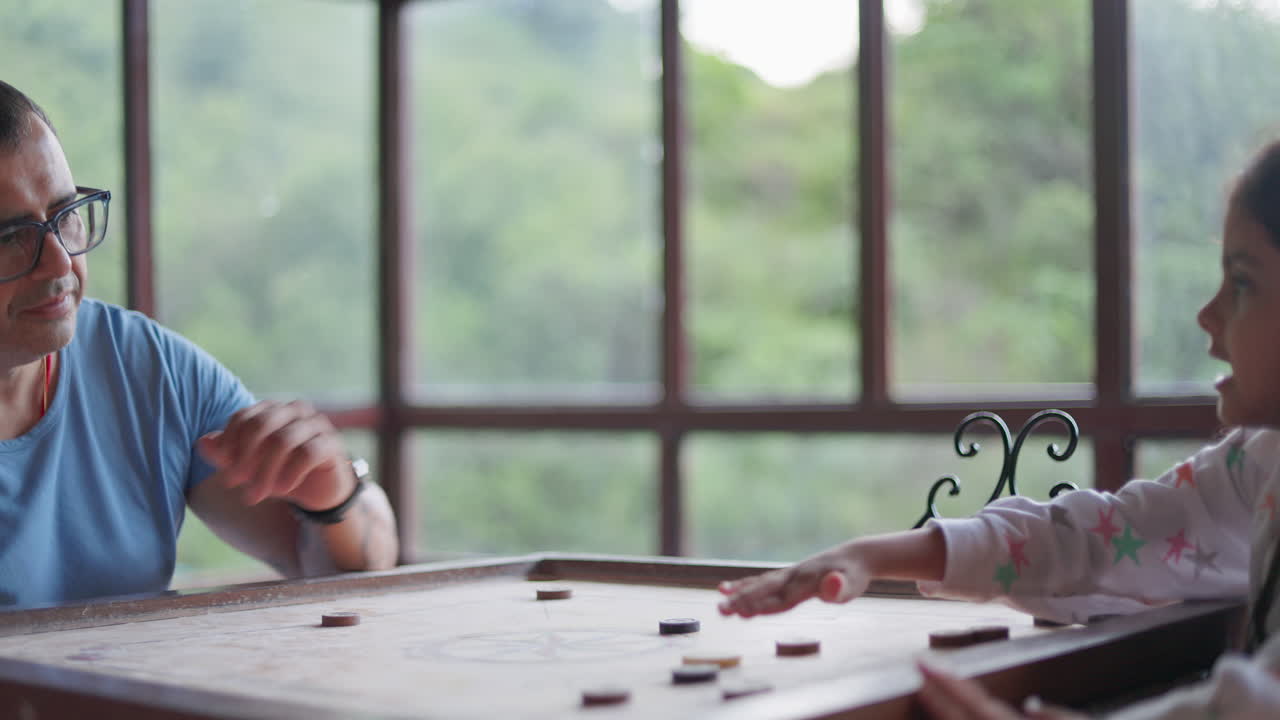 father and daughter enjoying an indoor board game together with a scenic green view in the background
