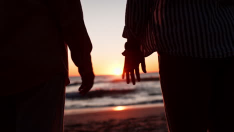 Holding-hands,-beach-and-couple-at-sunset