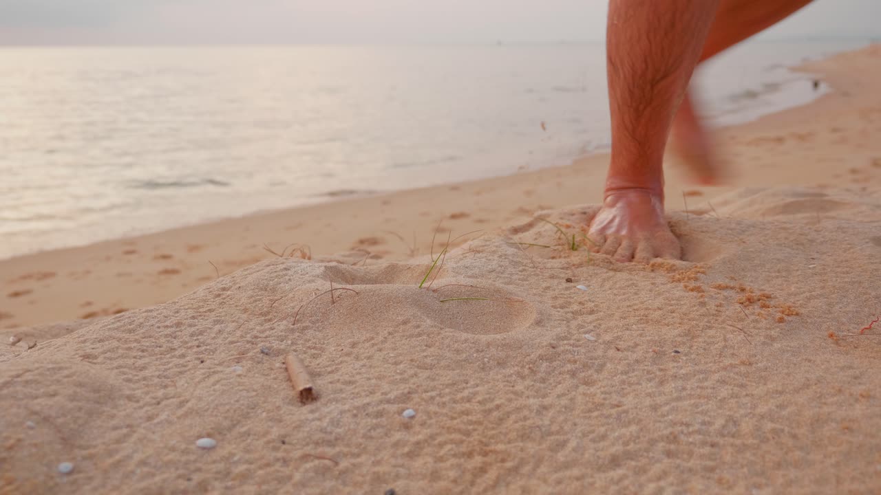 vista de ángulo bajo de un tipo caminando solo en la playa al atardecer