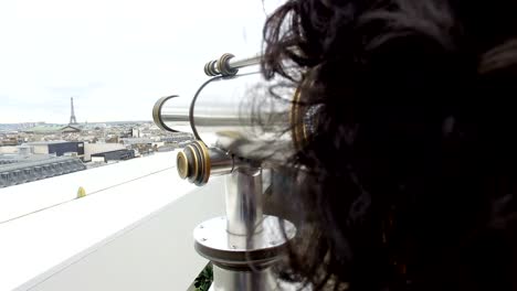 tourists looking over paris landscape with eiffel tower on lafayette gallery terrace with coin operated binocular telescope