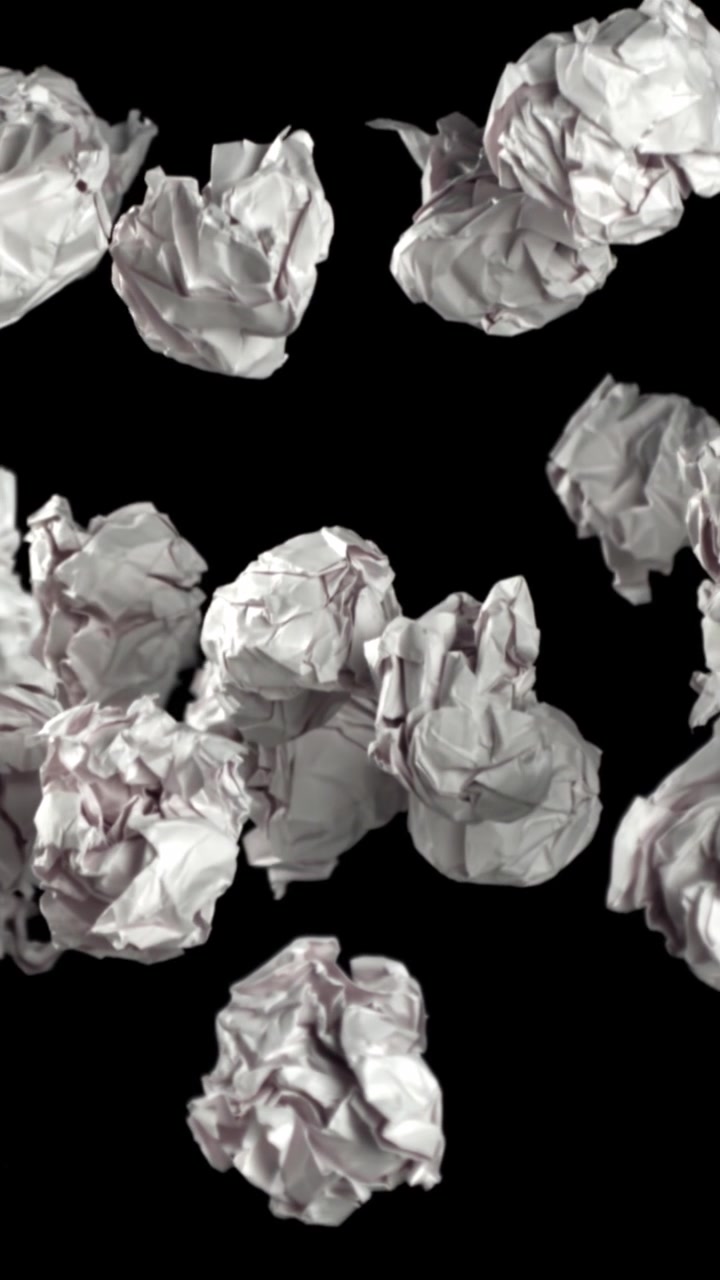 Bolas de Papel Branco Amassadas Caindo Contra um Fundo Preto