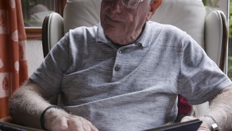 elderly man reading a book in an armchair