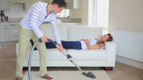 Woman-sleeping-on-the-sofa-while-man-doing-the-housework