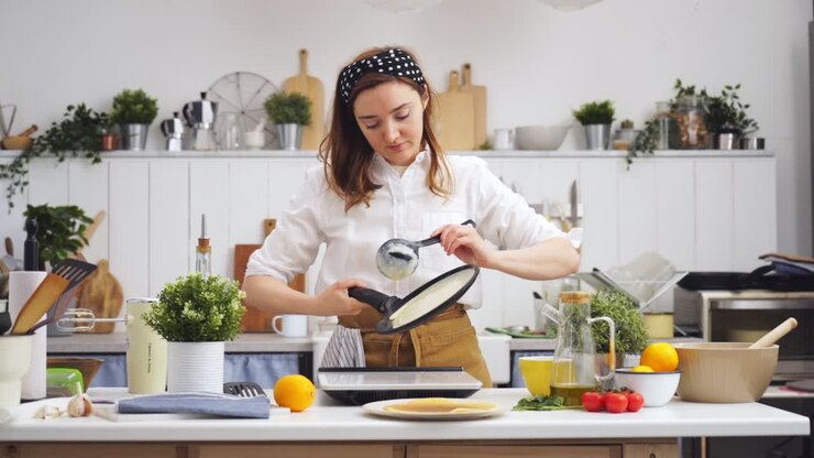 Cuisinier mettant la pâte pour une crêpe dans la poêle