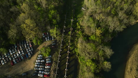 a junkyard with rows of cars near a forest in fayetteville, ar, daylight, aerial view