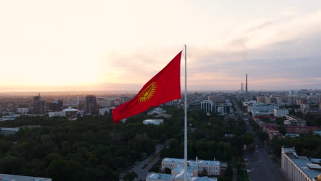 flag of kyrgyzstan with cityscape in the background at sunrise in bishkek, kyrgyzstan. - aerial shot