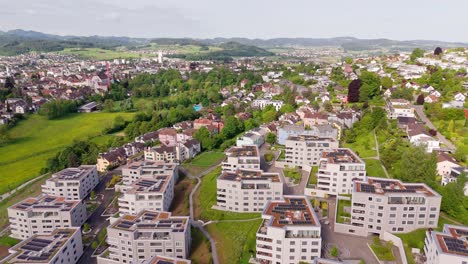 luxury apartment blocks with green green rooftop and solar panels. production of green energy theme. swiss city during sunny day in summer. similar real estates buildings in switzerland. aerial view.