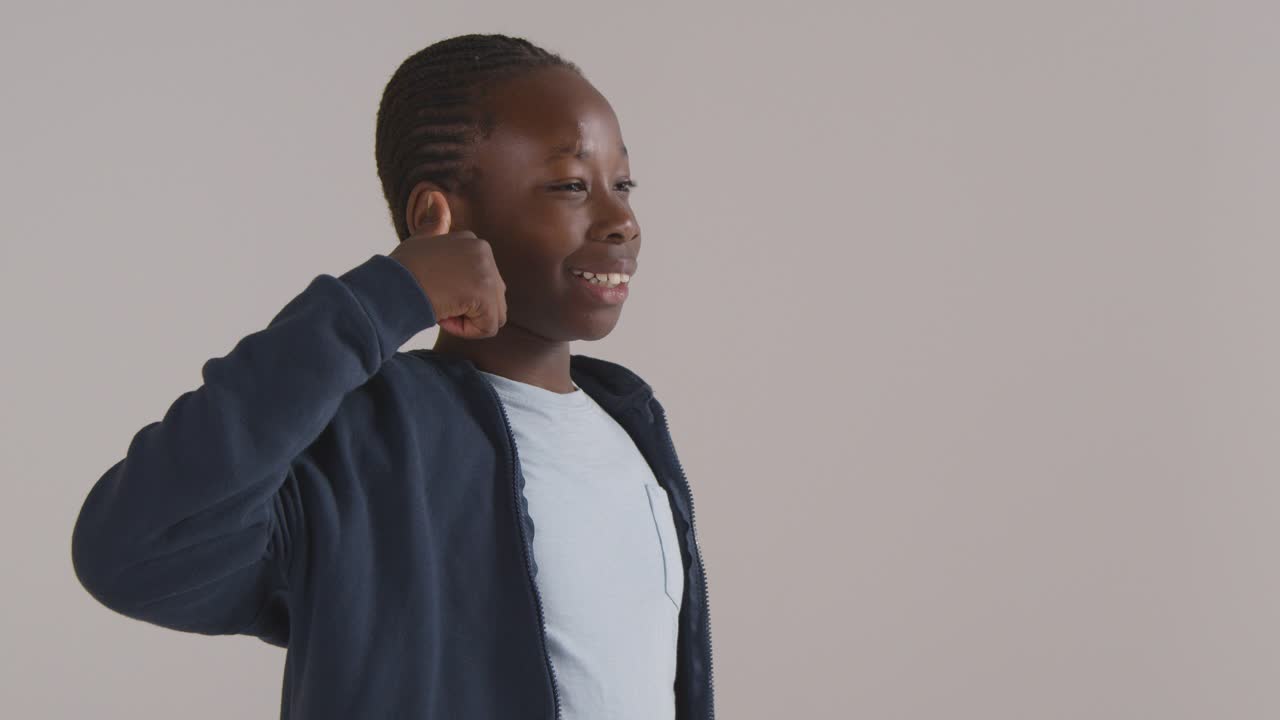 retrato de estudio de un niño sonriendo y dando un gesto con el pulgar hacia arriba contra el fondo blanco 1