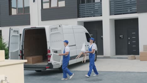 two young workers of removal company are loading boxes and furniture into a minibus