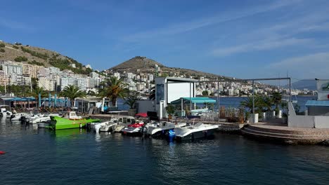 Tourist-and-Fishing-Motorboats-Grace-the-Anchored-Pier,-Painting-a-Tranquil-Scene-in-Saranda-Coastal-City's-Bay