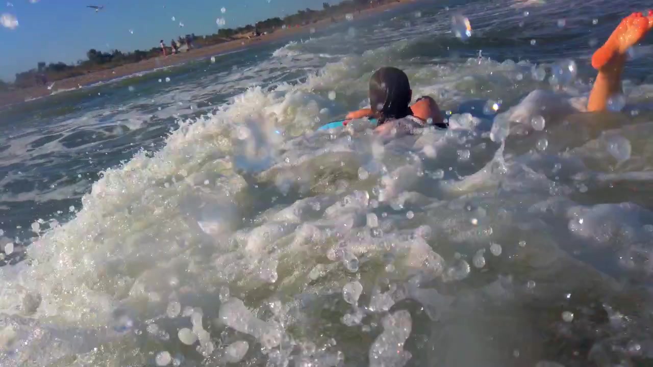 The surfer girl surfing on the surf board on the waves.
