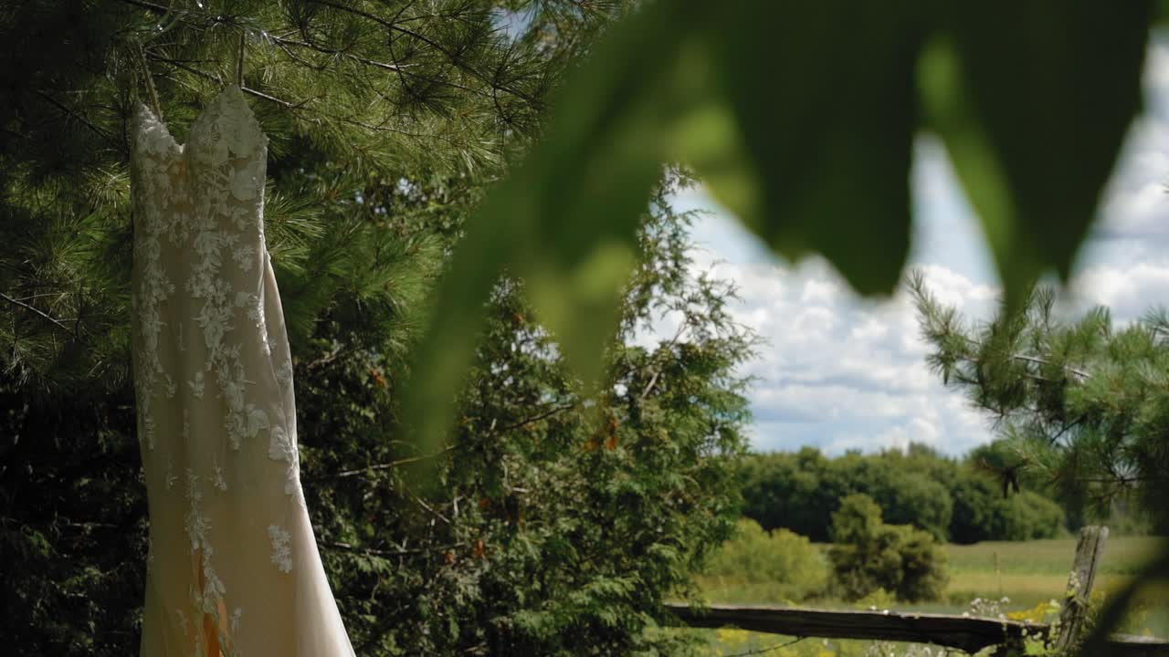 캐나다 오타와에 있는 스트래스미어 웨딩 및 이벤트 센터에서 아름답고 흐리고 화창한 날 나무 뒤에서 디자이너 패션 웨딩드레스를 우아하게 드러냈습니다.