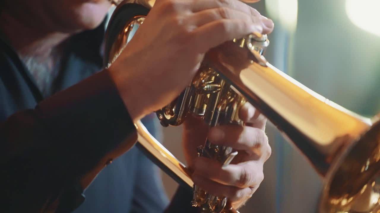 Primo piano di un uomo che suona una tromba d'oro con attenzione.