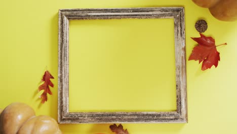 video of pumpkins with autumn leaves and frame with copy space on yellow background