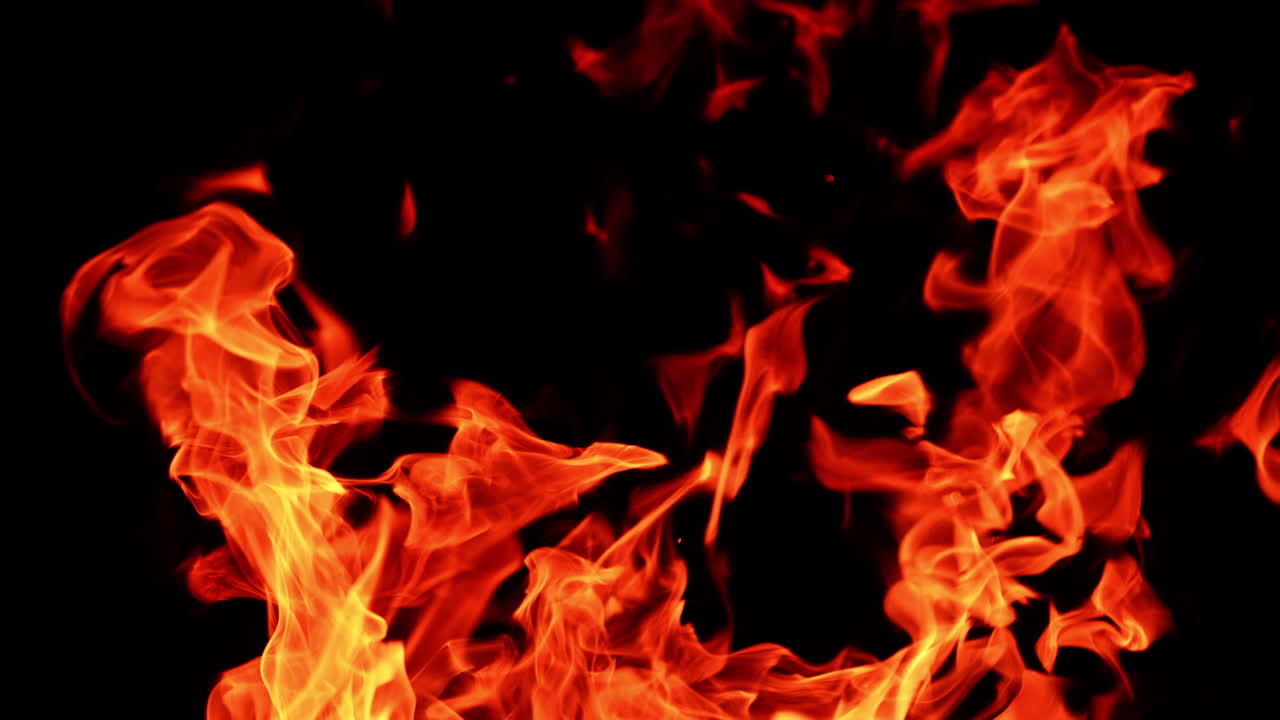 Red flames of bonfire dancing in the darkness. Close up view on the campfire burning at night.