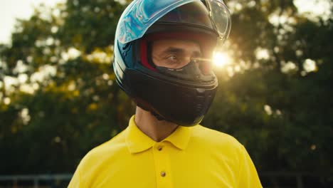 close-up portrait of a biker who removes protection from a motorcycle helmet and looks to the side in sunny weather