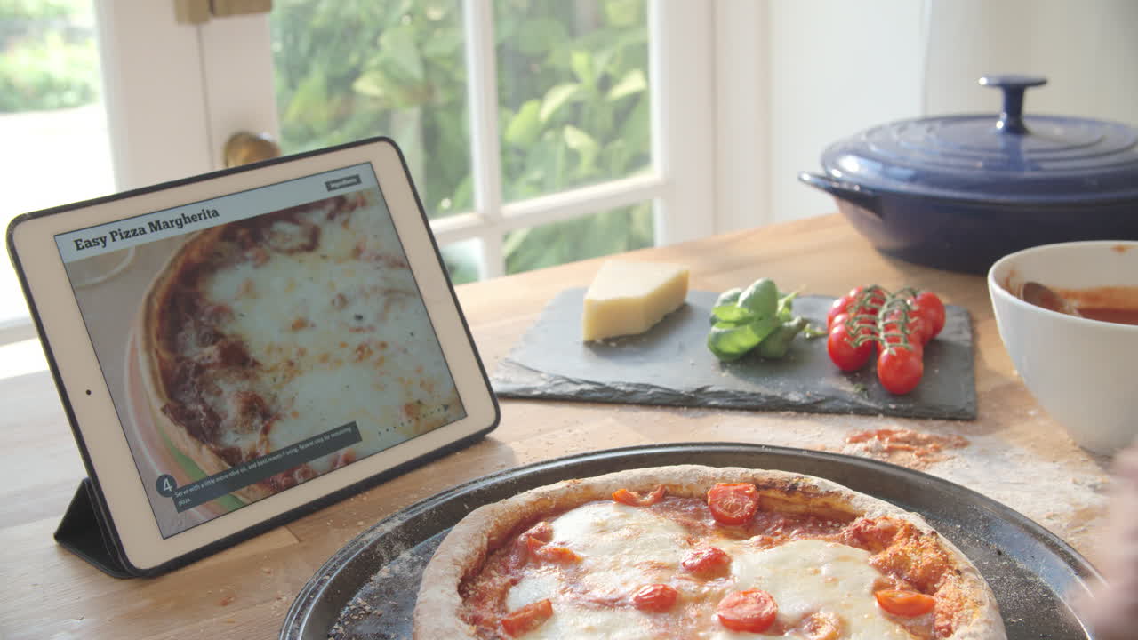 persona que sigue la receta de la pizza usando una aplicación en una tableta digital