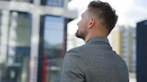 man in a grey suit looking up at buildings
