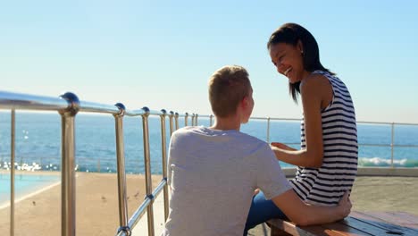 happy young couple interacting with each other while using mobile phone near railings 4k