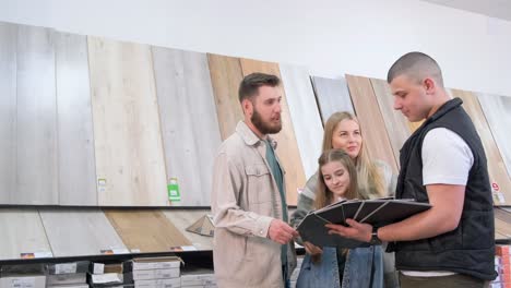 a young family is looking at exhibition samples of laminate in a building materials supermarket